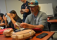 Class participant Michael Hartman begins to put on the AED pads to the CPR mannequin.