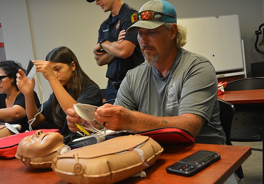 Class participant Michael Hartman begins to put on the AED pads to the CPR mannequin.