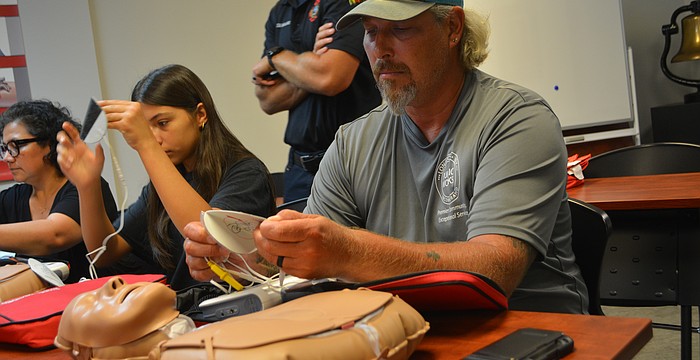 Class participant Michael Hartman begins to put on the AED pads to the CPR mannequin.