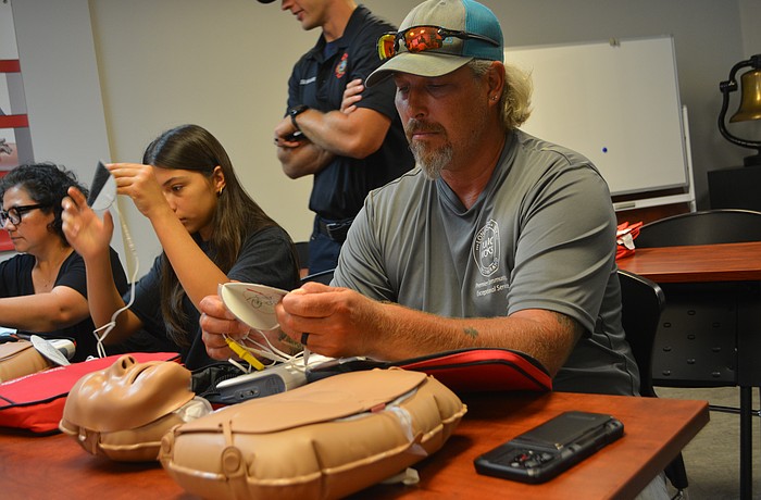 Class participant Michael Hartman begins to put on the AED pads to the CPR mannequin.