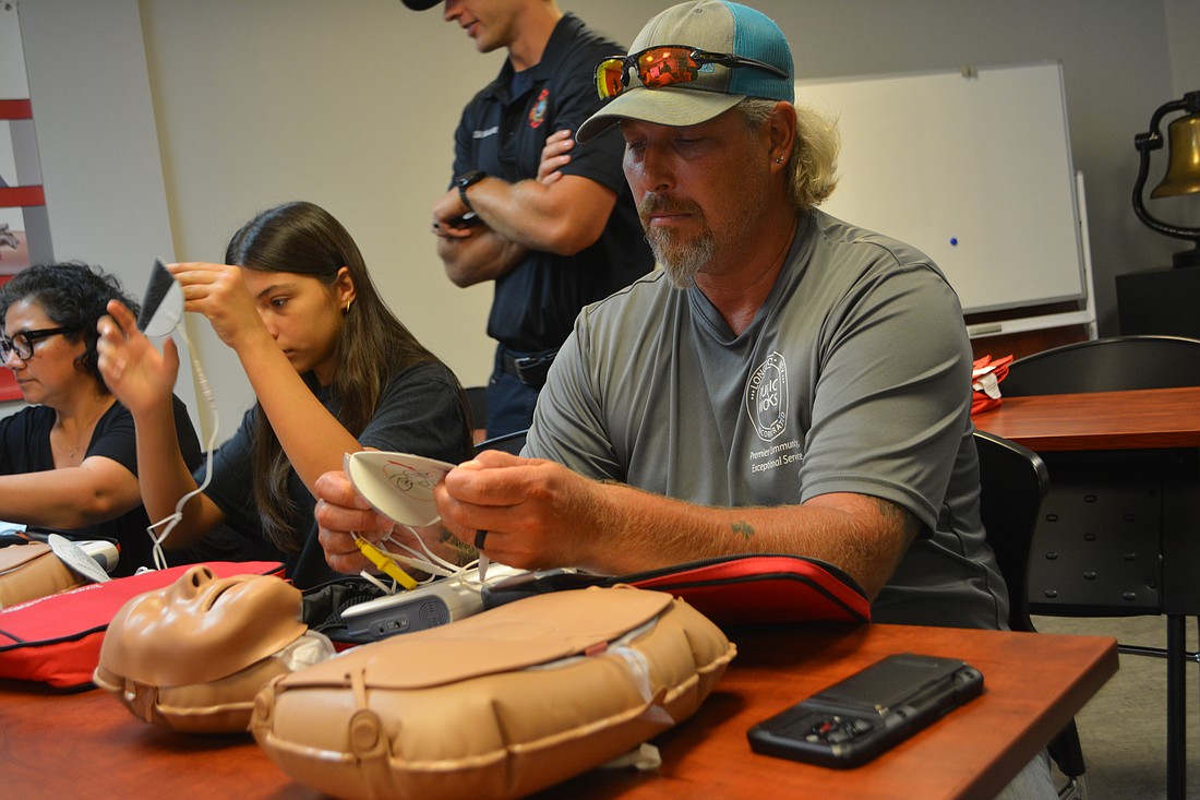 Class participant Michael Hartman begins to put on the AED pads to the CPR mannequin.