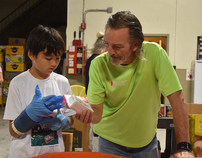 Sarasota resident Leo Marr, 11, works with Bo Bickley, the volunteer associate at All Faiths Food Bank. Marr broke his wrist playing soccer but didn't let that stop him from helping the community.