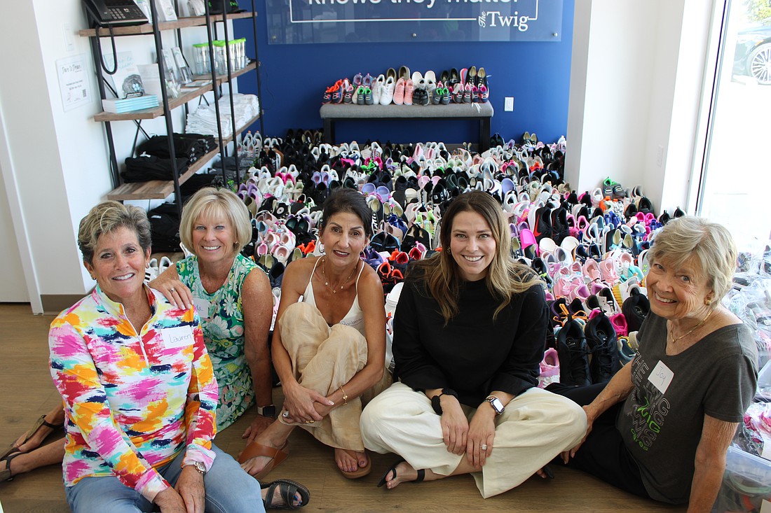 The Lake Club Women's Giving Circle members Lauren Hirsch, Cinda Krouk, Barbara Najmy, Jennifer Alokeh and Joy Stone sit in front of their record haul of 550 pairs of sneakers donated to The Twig.