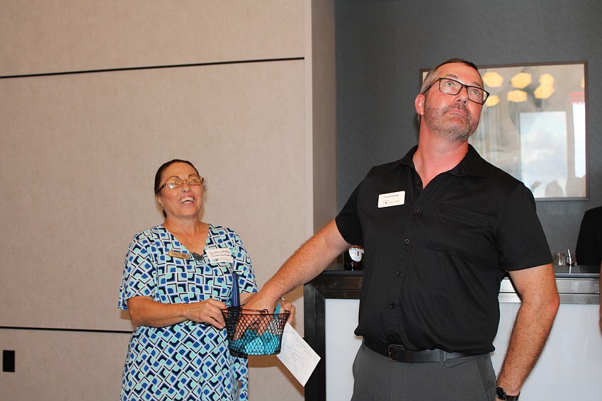 Brad Moltrup from Pillar to Post makes it clear he's not peaking while selecting the raffle winners at the Longboat Key Chamber of Commerce's Off the Clock networking event on July 23 at the St. Regis Longboat Key Resort. Debbie Shaffer, left, said the raffle benefitting Manatee Children's Services was one of the most successful yet.
