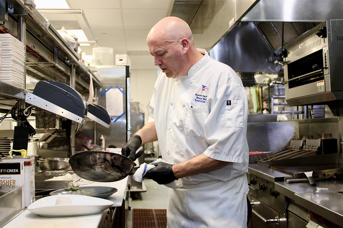Sarasota Yacht Club Executive Chef Bruce Bailey adds the finishing touches to his signature steak dish.