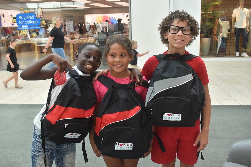 Sarasota residents Rickie Riddle VI, Paitynn Riddle and Rickie Riddle V each receive a free backpack at the Back to School Bash presented by Florida Kid Care.