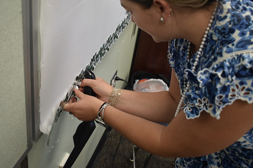 Fourth grade math and science teacher Riley Hamilton staples a border onto the classroom board.
