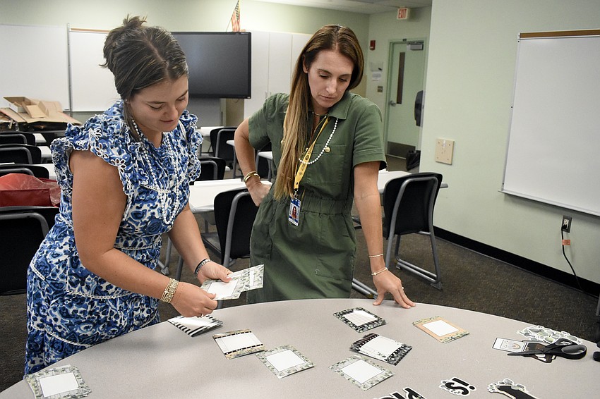 Fourth grade math and science teacher Riley Hamilton and fourth grade English language arts teacher Christine Harrington plan the display on their bulletin board that will welcome students back to the classroom.