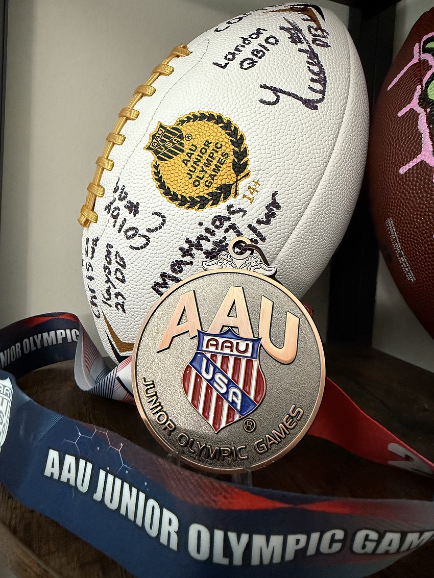 The Mad Dogs Elite 15U team's bronze medal with an AAU Junior Olympic Games football signed by the players. Courtesy photo