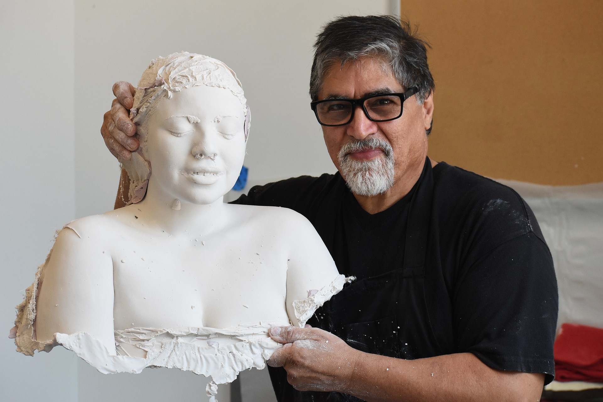 Rigoberto Torres holds the bust of Bélen Lopez. There is still more work to be done, including opening the eyes on the sculpture and painting the surface.