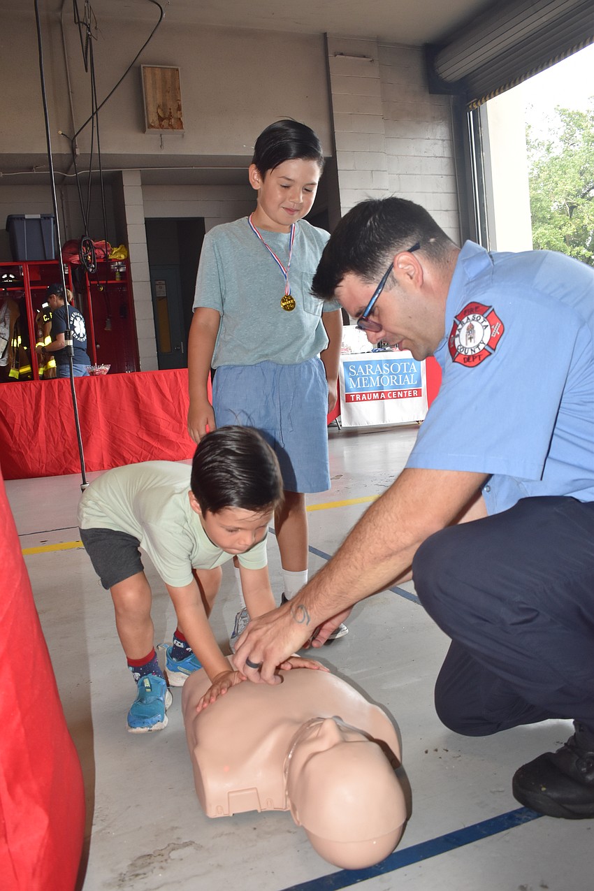 Matthew Heinlein, 4, and Benjamin Heinlein, 7, learn about CPR from Firefighter/EMT Victor Vassallo.