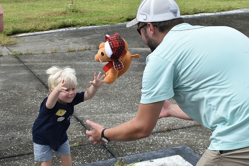 Eli Lucas, 2, plays a game of catch with his uncle David Blumenstock, using a stuffed animal received at the open house.