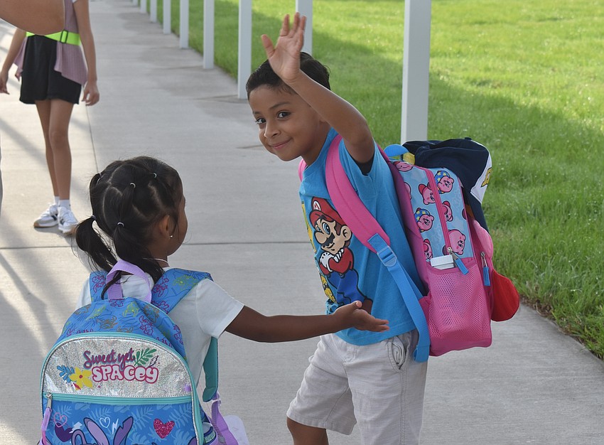 Third grade student Alex Montano waves goodbye to his mother Connie De Leon before he walks his little sister, pre-K student Samantha Montano, into the building for their first day at Lake Manatee.