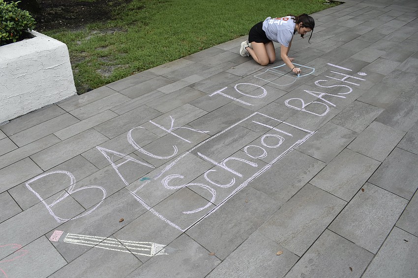 Jenny White draws a sign on the pavement.