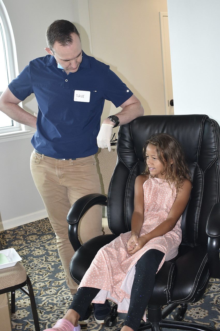 Dentist Dave Schroeter greets Myleah Roman, 7.