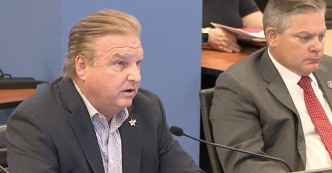 Sarasota County Tax Collector Mike Moran (left) talks budget with county commissioners as County Administrator Jonathan Lewis looks on.