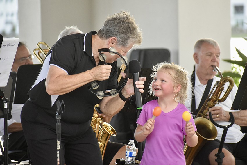Conductor Lynn Cleary invites 4-year-old Reagan Sibley on stage to play maracas with the band.