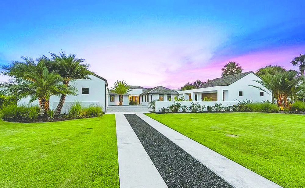 Single-story home with golf course views features five bedrooms, four bathrooms, guest suite, office, porch, patio, outdoor kitchen and five-car garage.