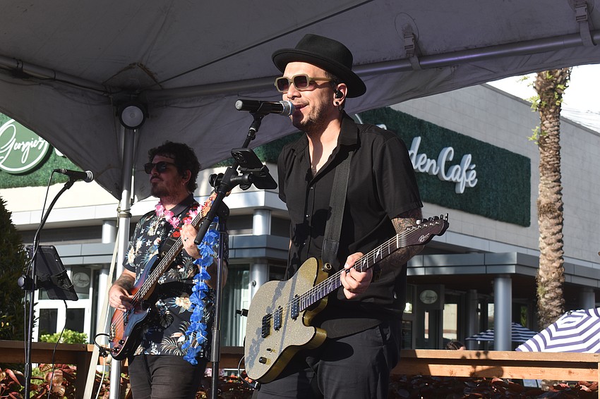 Sugar Vibe's Pedro Rizza plays bass and Will Nacar plays guitar and sings at the night market on The Green at University Town Center.