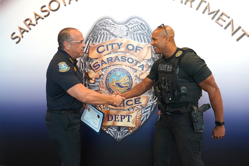 Sarasota Police Chief Rex Troche congratulates Officer Adam Bearden on his and K-9 Butch's completion of training certification.