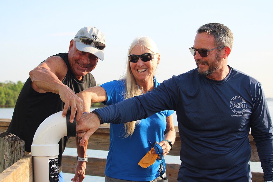 Jeff and Terri Driver from the Rotary Club of Longboat Key join Public Works Director Charlie Mopps in placing the first discarded monofilament fishing line into newly installed recycling receptacles at Overlook Park. As part of its environmental improvement initiatives, the club is working to get as much ghost fishing gear out of Longboat's waterways as possible.
