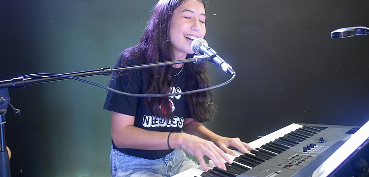Nina Young, 13, of the band Pins and Needles, performs on stage.
