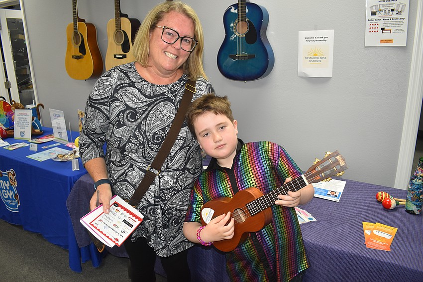 Carrie Collins and her son Kerin Collins, 7, visit the Siesta Wellness Institute table where Kerin held a ukulele.