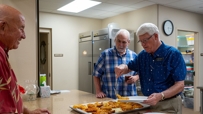 George Rauch serves a filet for Rich Raymond at Christ Church of Longboat Key as Mark Huber looks on Thursday, Aug. 27, for the annual church fish fry.