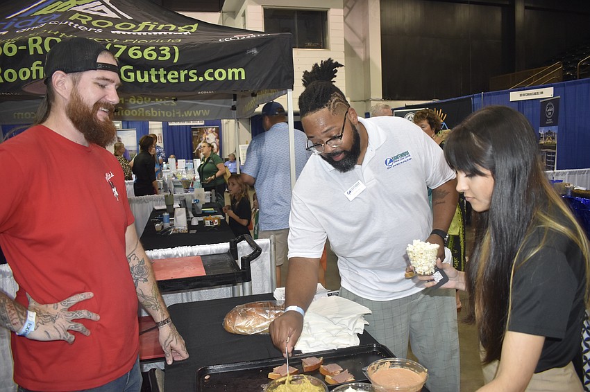 Joel Hanson of The Original Wolfie's Deli serves Tory Menifee of Lighthouse and Kyla Diaz of The Love Vault