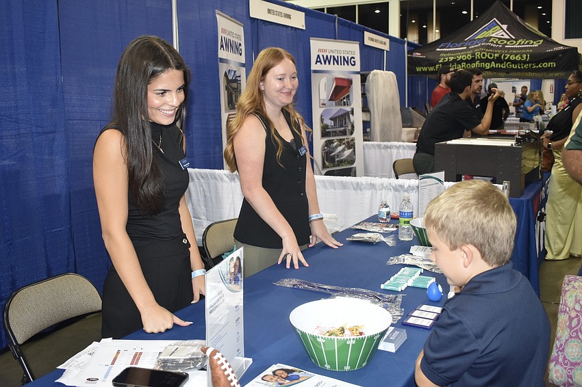 Christina Castillo and Jenna Smith of Millenium Physician Group table offer goodies to Liam Middleton, 7.