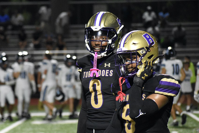 Senior Chauncey Kennon and junior Zaddy Turo of Booker High School walk across the field.