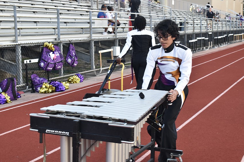 Tenth grader Bastian Piña helps wheel out the band instruments.