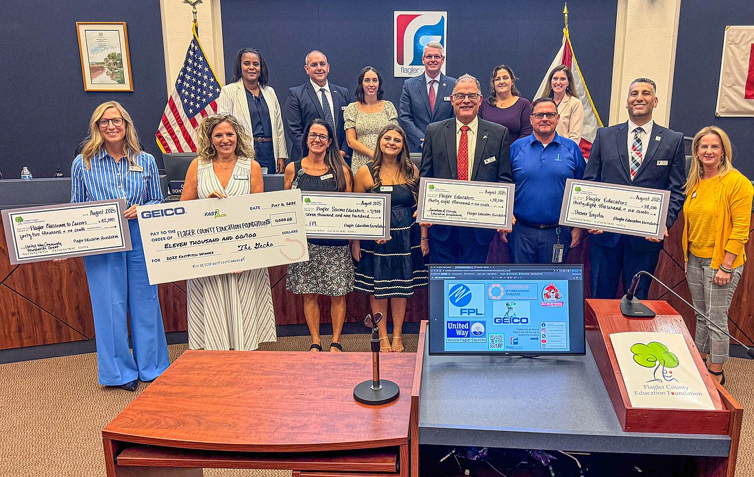 Flagler Schools administrators hold up grant checks secured by the Flagler County Education Foundation at the Aug. 26 School Board meeting. Flagler Schools photo