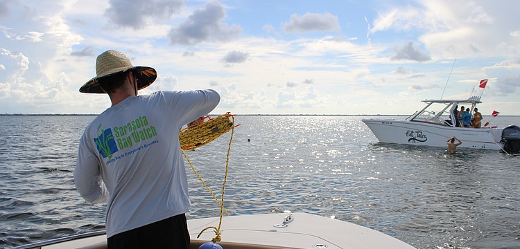 Volunteer Peter Bonk spools out line for the grid-based search for scallops in Sarasota Bay during the Great Scallop Search of 2025.