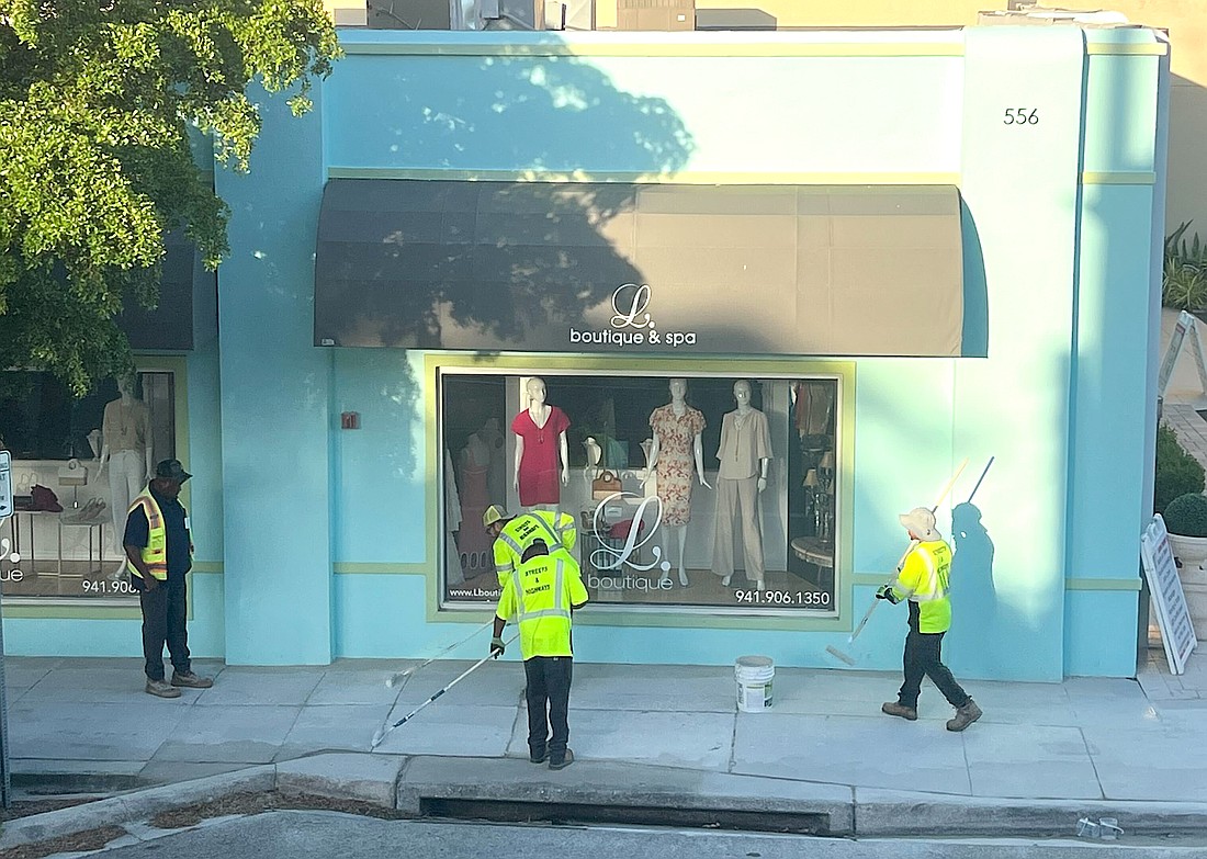 City of Sarasota Public Works personnel work on removing sidewalk murals in Burns Court.