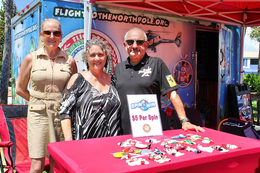 From left, Flight to the North Pole organizers Danyel Libertore, Sylvia Gillotte and Sidney Ettedgui sold Christmas ornaments at the Exotic Cars on the Circle show on Sept. 6. The nonprofit gives families the opportunity to enjoy a special day with the Clauses in December.