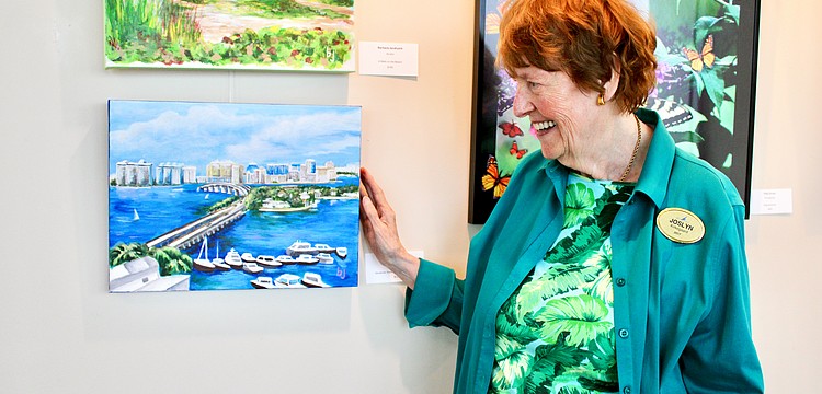 Plymouth Harbor resident Joslyn Kirkegaard purchases a painting by Barbara Jendrysik at the debut art exhibition evening organized by the local chapter of the National League of American Pen Women on Sept. 9 at Plymouth Harbour. The show will be open for the next few months.