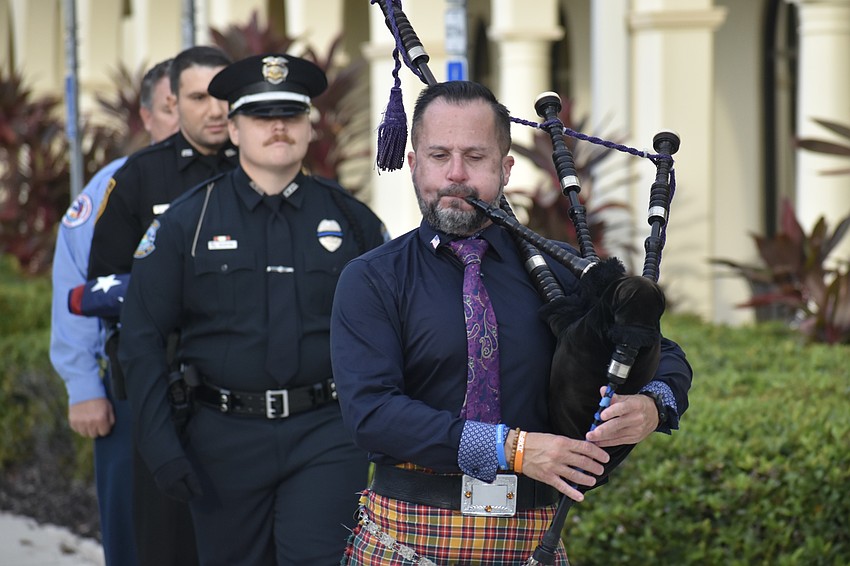 Firefighter Jason Moore of Cedar Hammock Fire Rescue, Officer Alex Stevenson of USF Sarasota-Manatee and officer J.T. Shapiro of the Sarasota Police Department follow USF Alumnus Ross Allen on bagpipes as the flag raising begins.