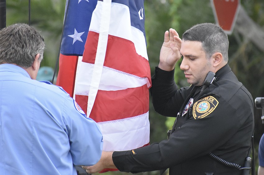 Firefighter Jason Moore of Cedar Hammock and Officer Alex Stevenson of USF Sarasota-Manatee raise the flag.
