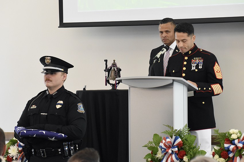 Officer J.T. Shapiro of the Sarasota Police Department and Carlos Moreira, Director for Campus Engagement for Veteran Success at USF Sarasota-Manatee stand by as Sergeant Major Enrique E. Alvarez of the United States Marine Corps reads 