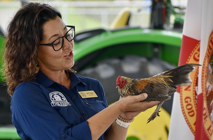 Farm Manager Kate Traugott speaks while holding a rooster named Napoleon.