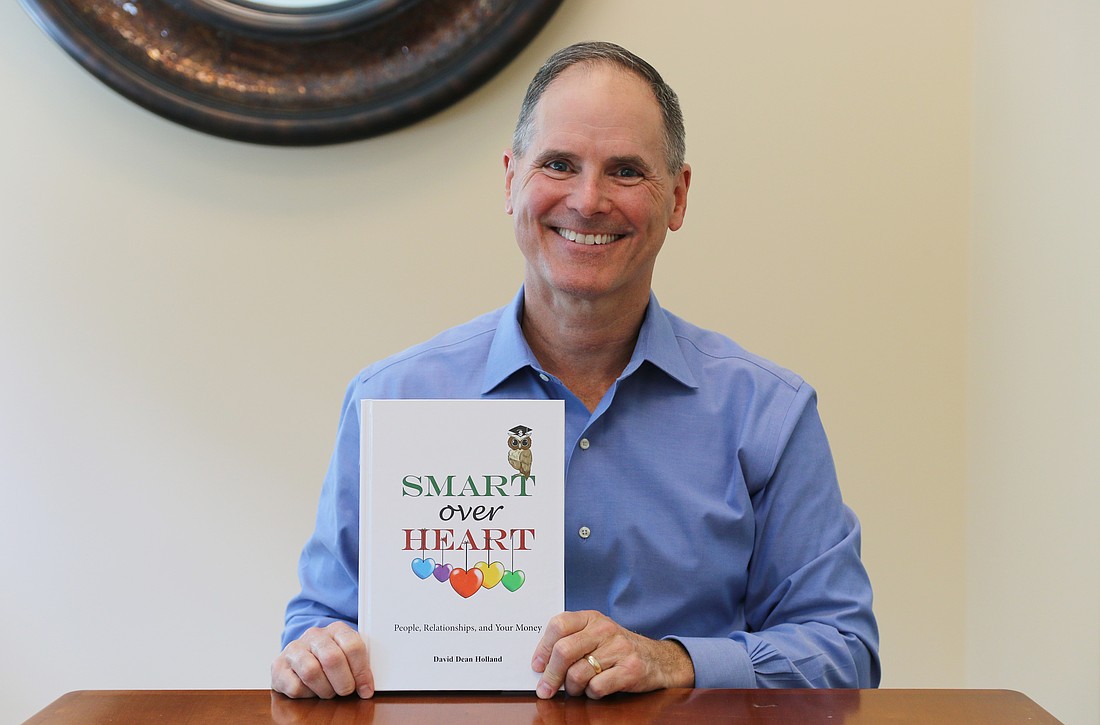David Holland holds a copy of his new book, "Smart Over Heart." Photo by Jarleene Almenas