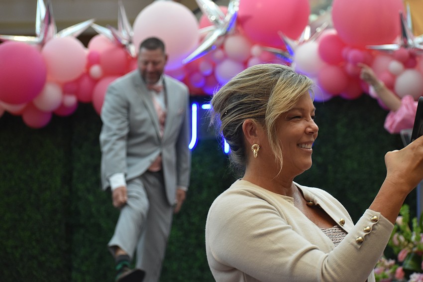 Sheri McFarland takes a video of the audience while her husband Luke McFarland of McFarland Mortgage Group sports a suit from Men's Warehouse.