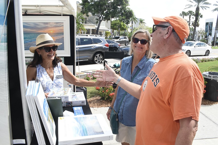 Photographer Mary Lou Johnson of Longboat Key showcases her puzzles to Russ and Lynne Brown.
