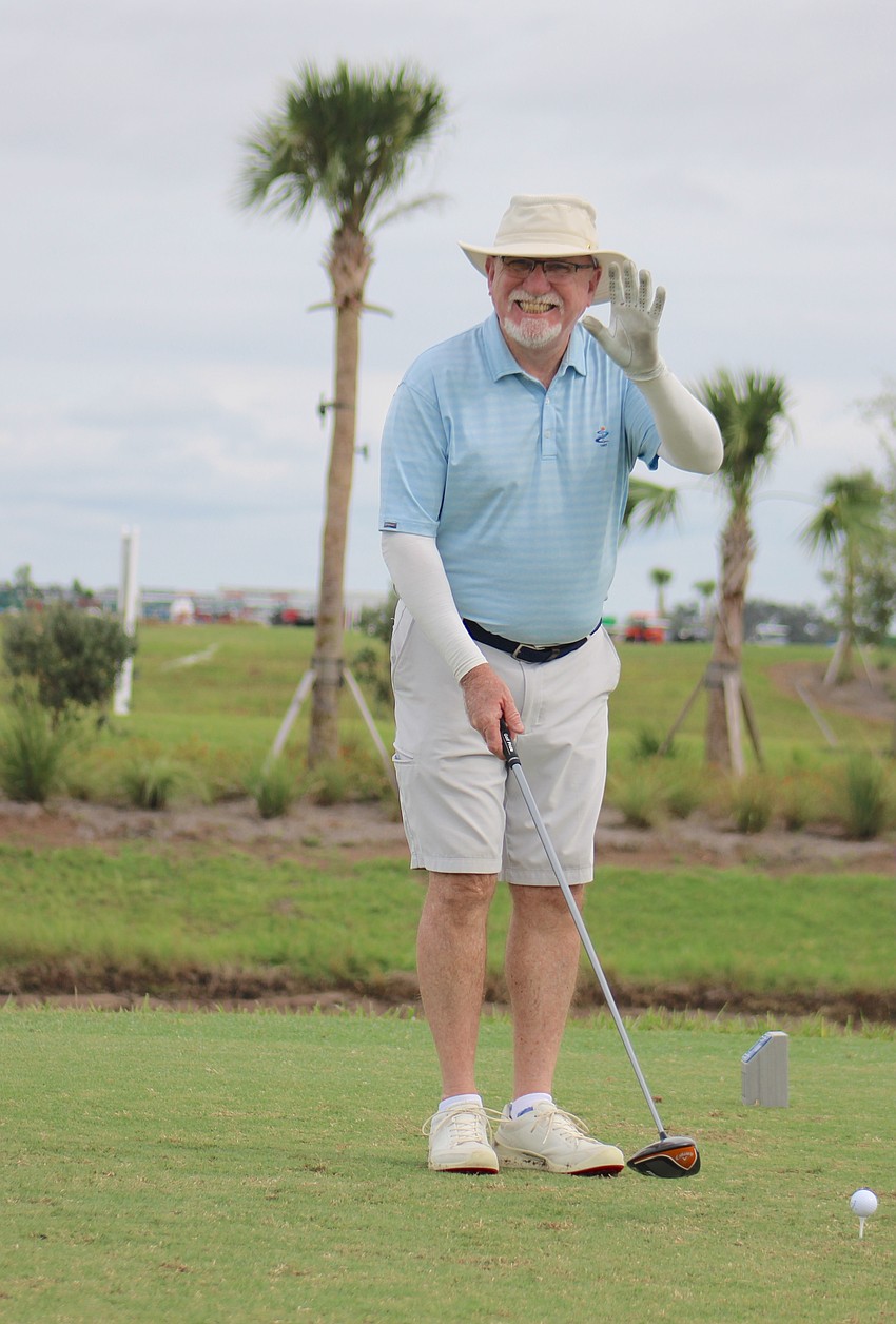 Gerry Hause gives a wave before taking a swing at the ball.