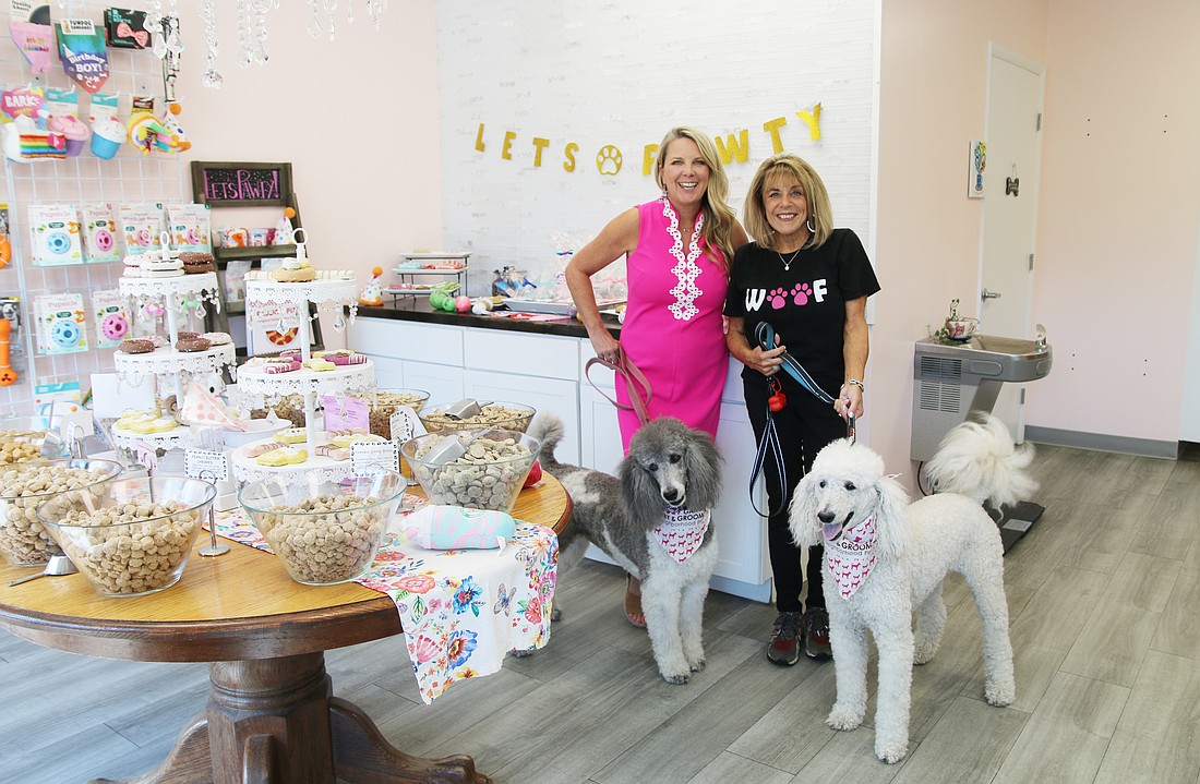 Tonya Perry, Nancy Mcphee and her dogs Karma and Peanut smile from inside the Woof Gang Bakery and Grooming store in Ormond Beach. Photo by Jarleene Almenas