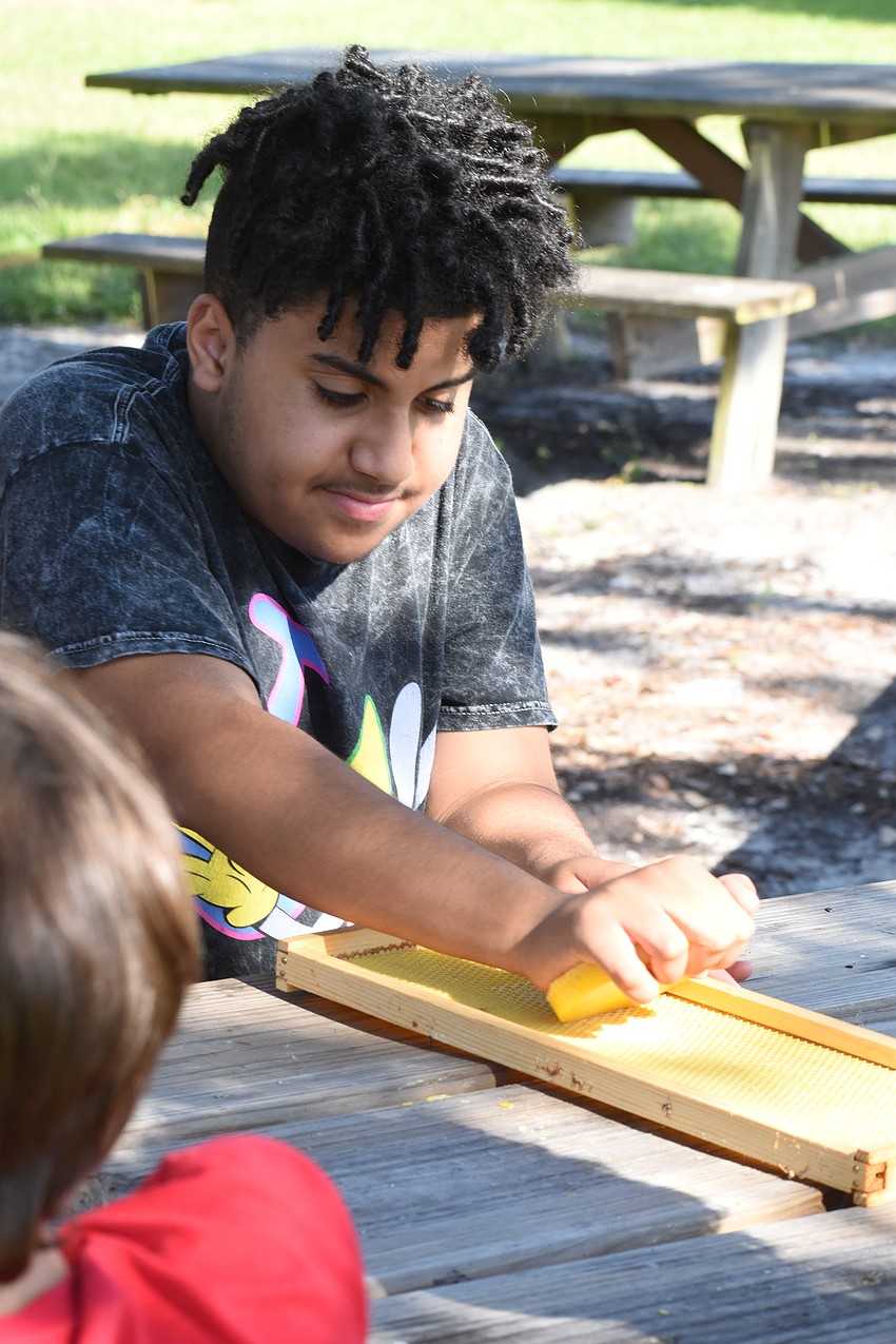 Blake Brown, 13, rubs beeswax onto a frame.