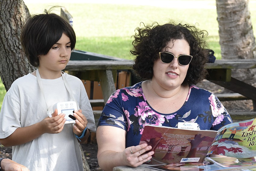 Noah Greber, 10, looks on as Laura Bishop reads a book.
