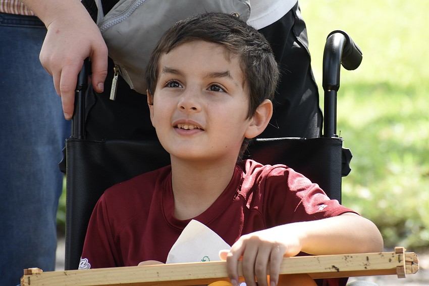 Charlie Greber, 6, holds a frame from the beehive as he listens to beekeeper Lauren Hofing speak.