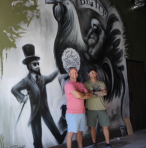 Big Top Brewing Company co-owners Mike Bisaha and Seth Murauskas stand next to the art that greets patrons when they enter the Fruitville Commons location.